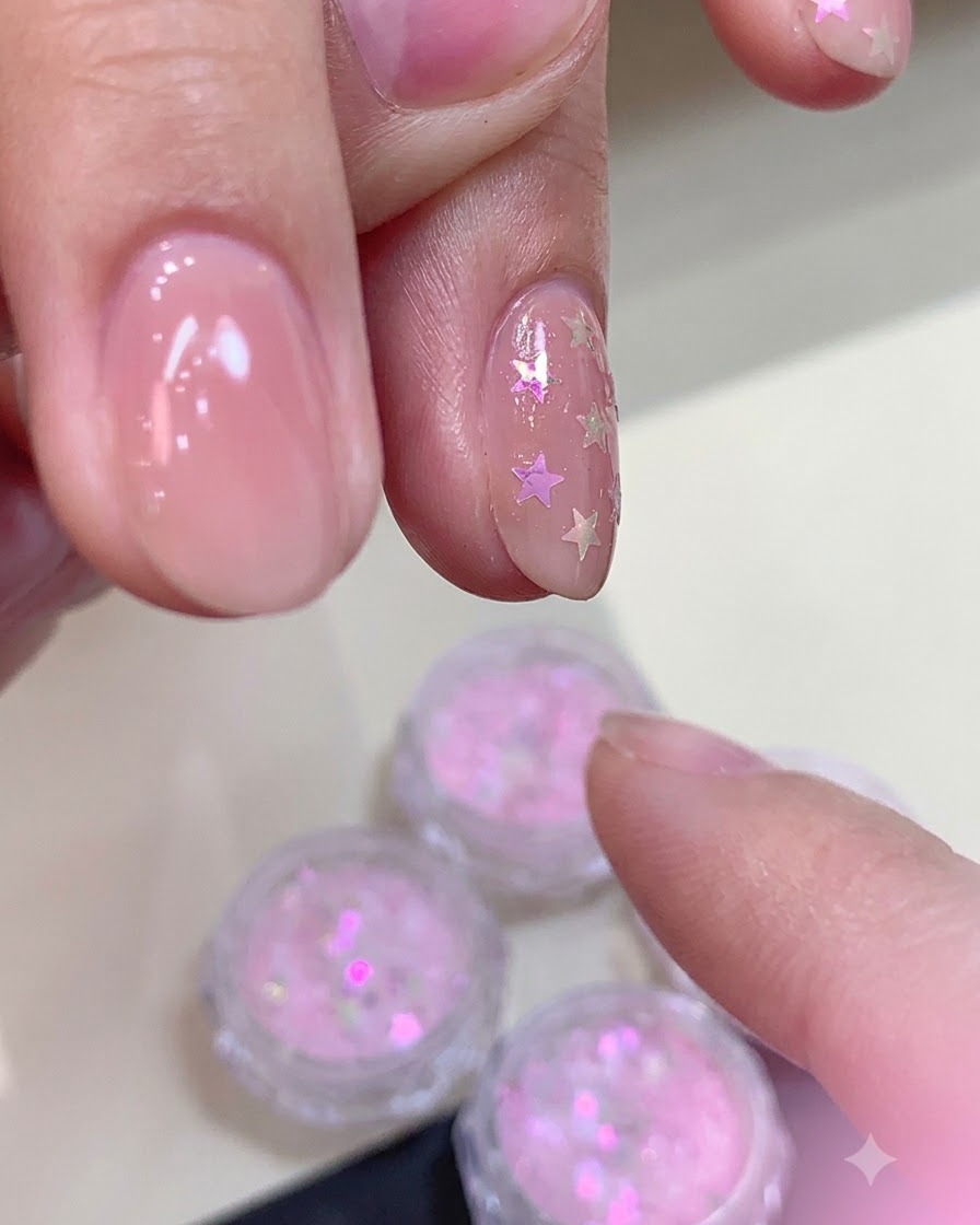 Applicazione di uno strato spesso di top coat opaco su ununghia decorata con glitter a stella autocurvanti.