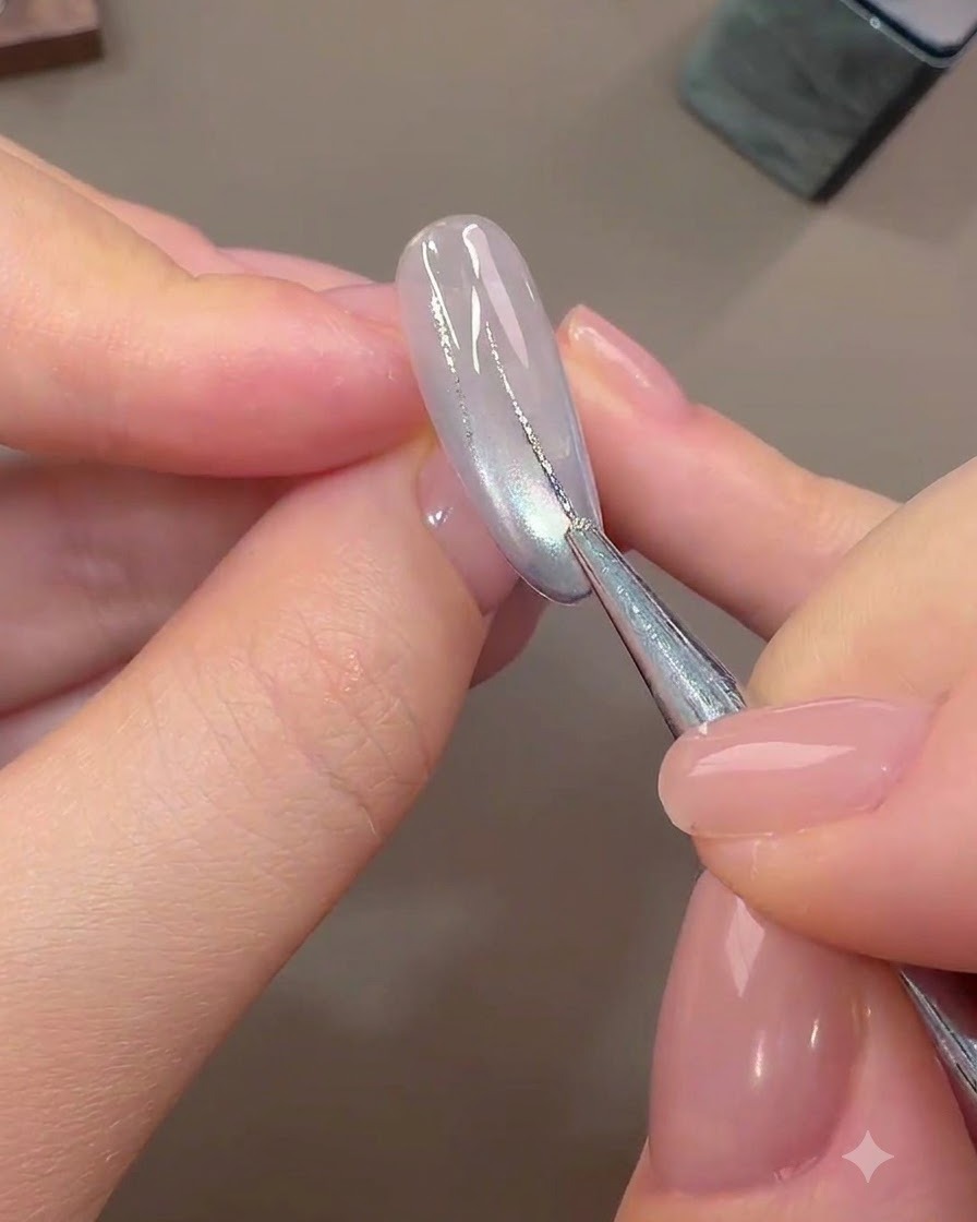Un pennello fine per nail art disegna linee astratte sottili con gel foil argentato su ununghia di base polimerizzata e chiara.