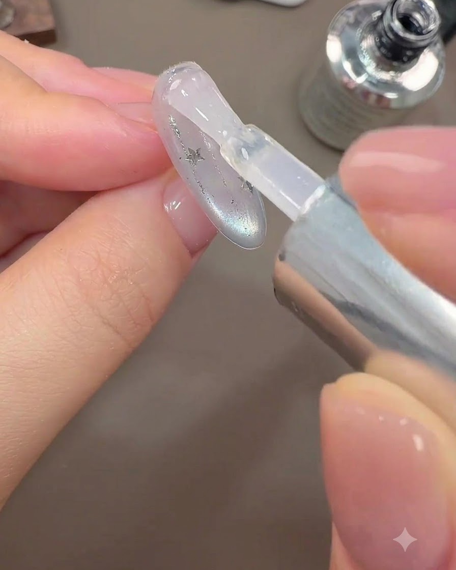 Un pennello applica uno strato di top coat lucido finale su un design di unghie galassia.