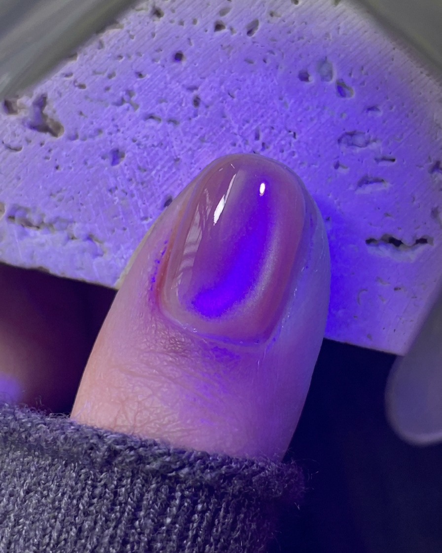 Ununghia che polimerizza sotto una mini lampada UV/LED viola.
