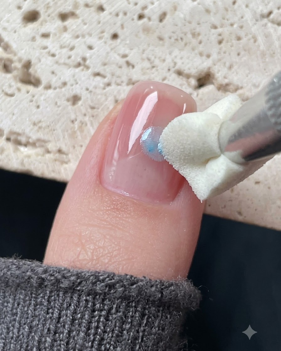 Uno strumento di stamping in silicone che tampona il gel di vetro blu attorno a un adesivo a stella su ununghia.