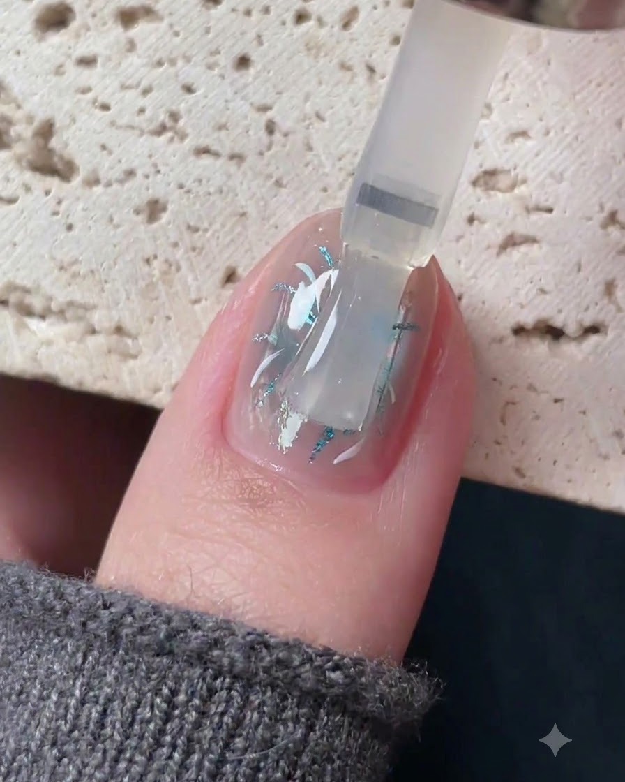 Un pennello che applica un top coat trasparente autolivellante su un design di nail art dettagliato.