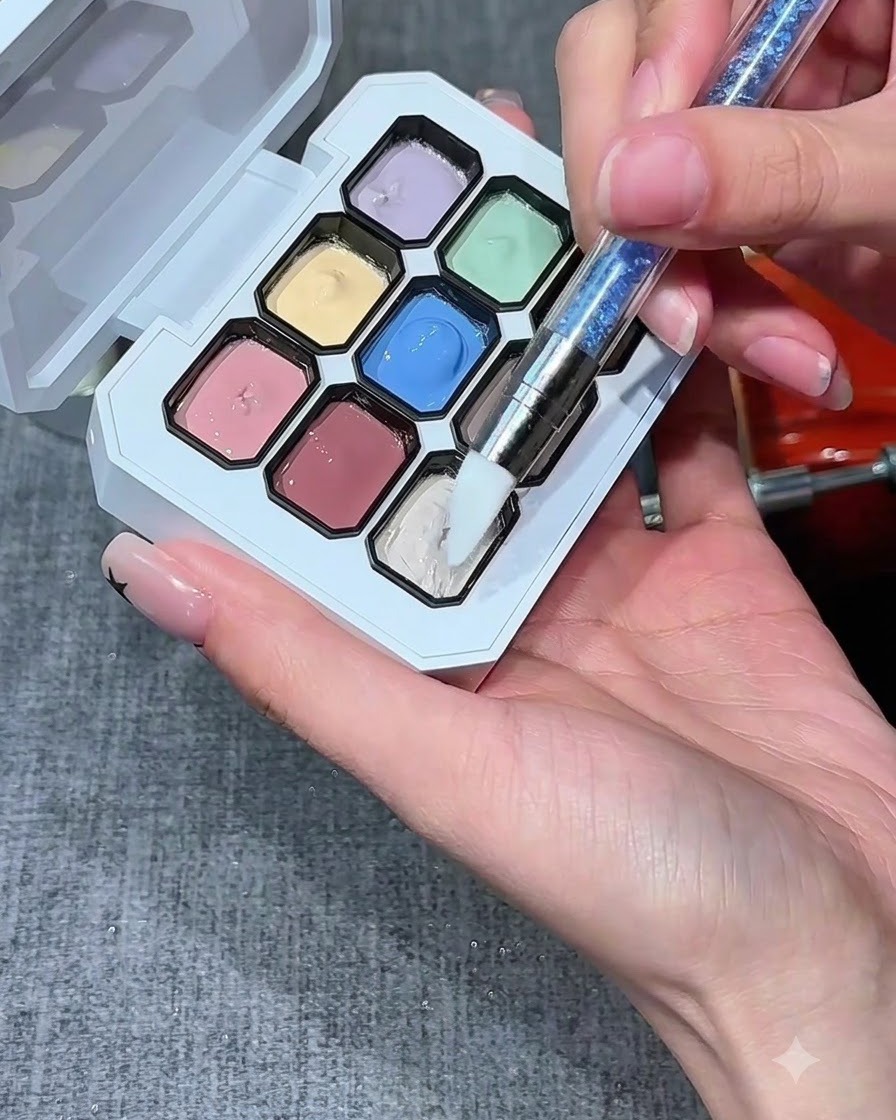 Un pennello in silicone per unghie che si intinge in un po di gel bianco lattiginoso su una tavolozza multicolore.