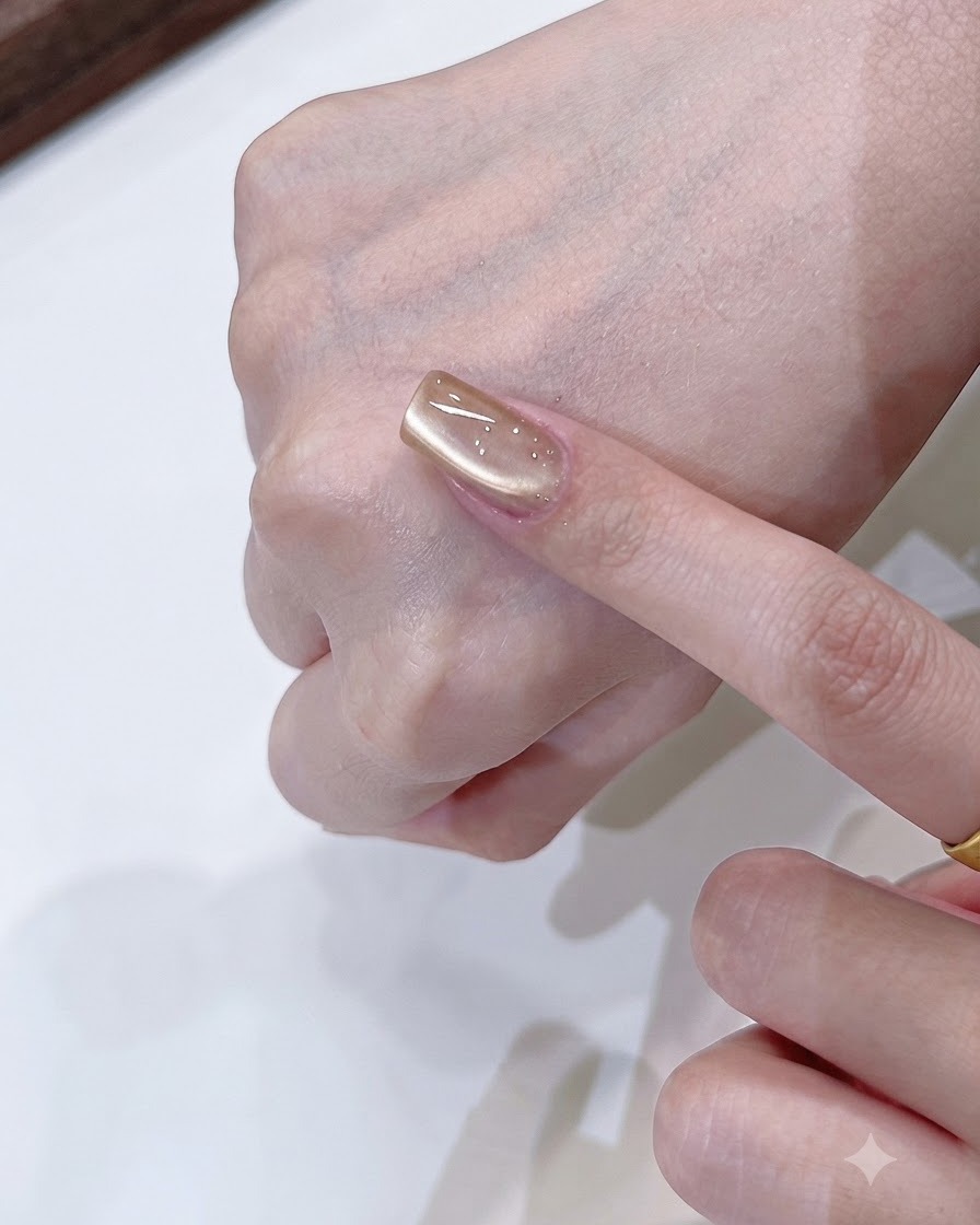 Uno strumento magnetico che modella un riflesso di luce morbido su un solo lato su ununghia cat eye oro champagne.