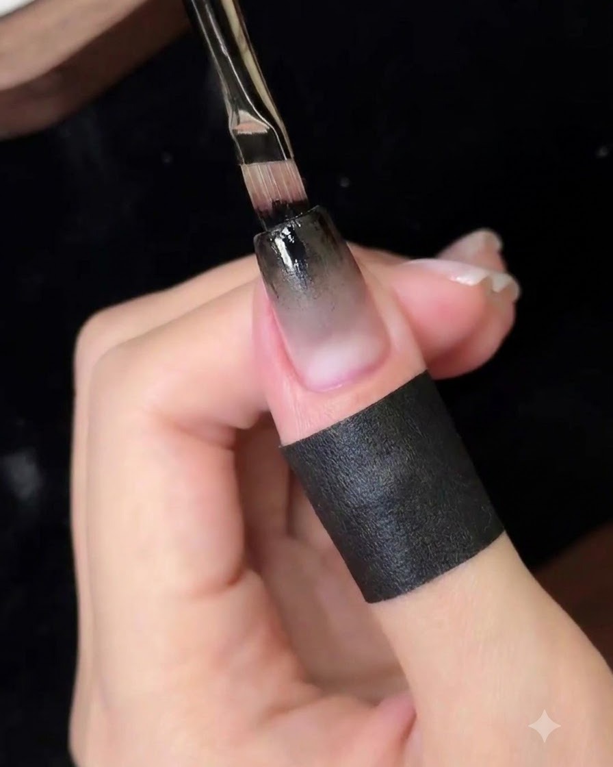 Un pennello a punta fine che applica uno strato concentrato di gel nero sul bordo superiore dellunghia.