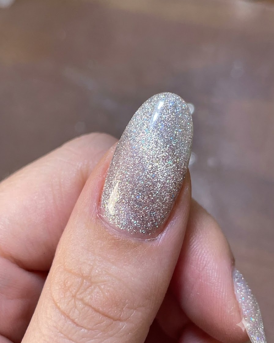 Uno strumento magnetico sospeso sopra ununghia in gel brillante per spostare le particelle di glitter magnetico al loro posto.
