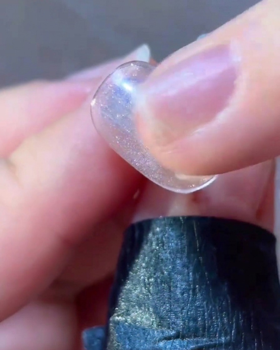 Un pennello liner sottile che applica dettagli in gel rosa attorno al design di una stella su ununghia.