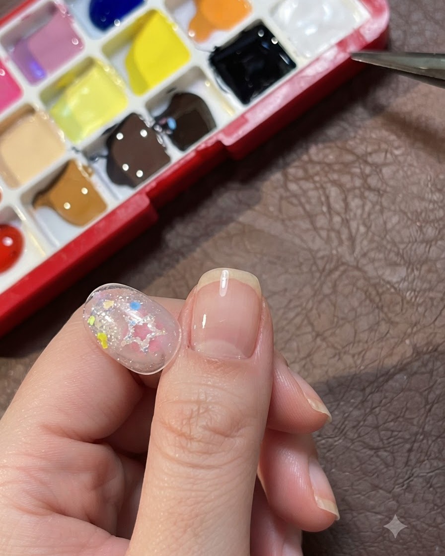 Una tavolozza di colori multipli posizionata accanto a una punta di nail art trasparente decorata.