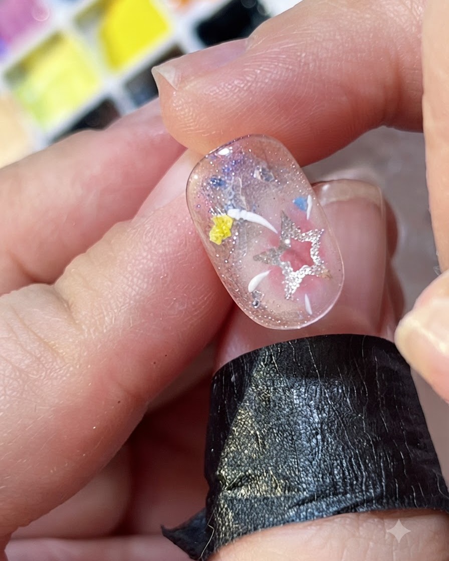 Primo piano di linee bianche e gialle dipinte a mano che si irradiano come fuochi dartificio su ununghia decorata.