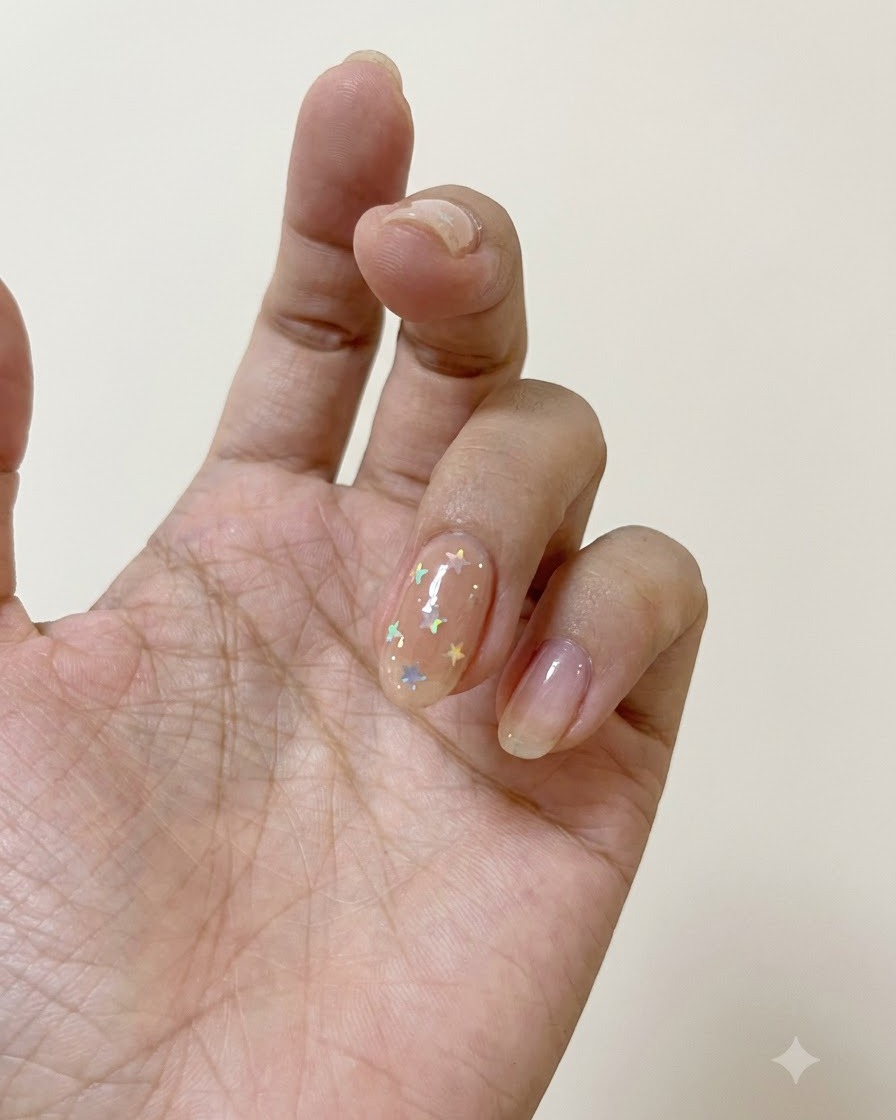 Un pennello per unghie che applica il top coat opaco su ununghia decorata con stelle polarizzate.