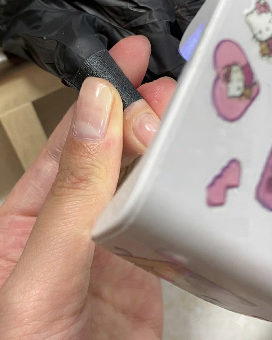 Una mano posizionata sotto una mini lampada UV/LED compatta per unghie durante il processo di polimerizzazione del gel.