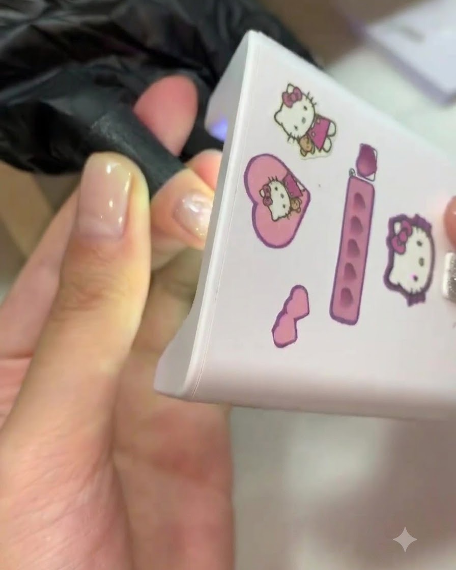 Un dito inserito allinterno di una mini lampada UV/LED rosa per la polimerizzazione.