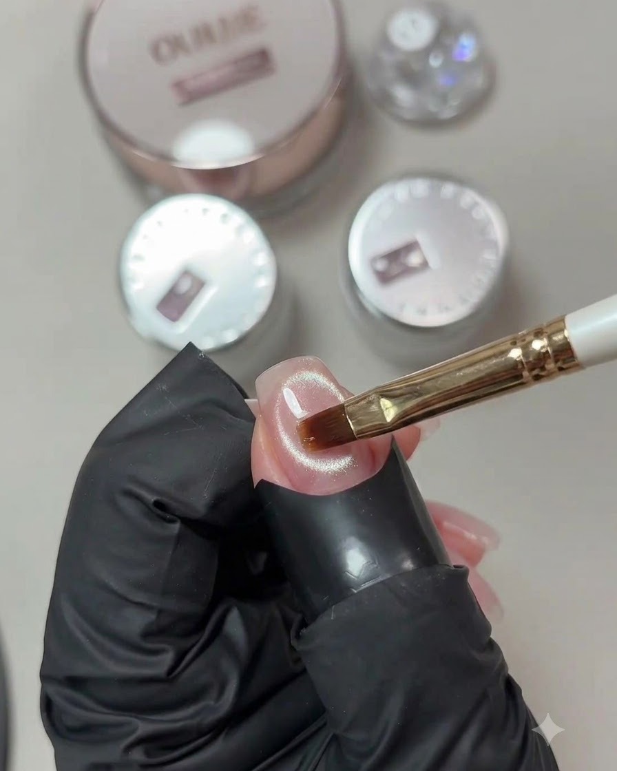 Un pennello da gel che applica uno strato trasparente di gel rinforzante su una superficie finita di unghia cat-eye.