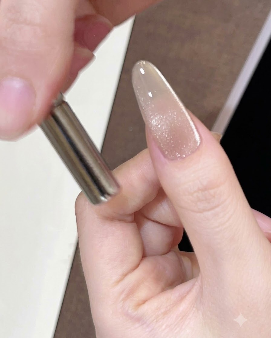 Un magnete cilindrico tenuto vicino al lato di ununghia smaltata per muovere i riflessi magnetici.