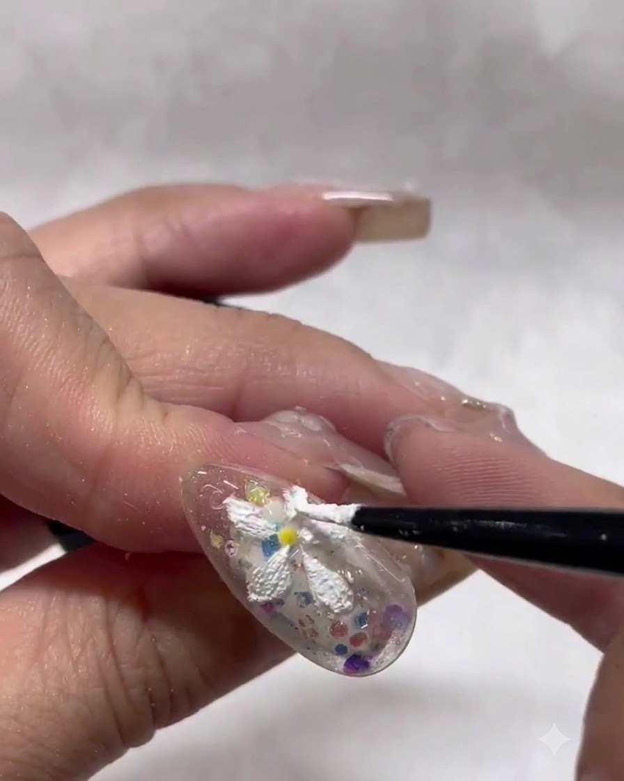 Un pennello liner sottile che modella e sistema con cura i bordi dei petali di margherita bianchi texturizzati su ununghia.