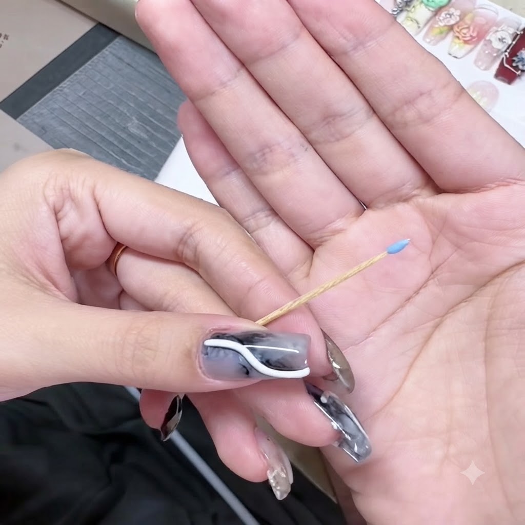Uno stecchino tenuto in mano con una minuscola perla di gel blu sulla punta appuntita.