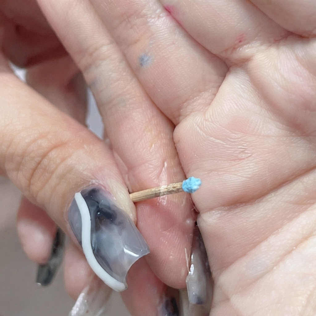 Un minuscolo bocciolo di rosa blu chiuso scolpito sullestremità di uno stecchino.