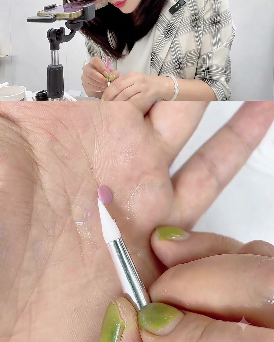 Una penna da intaglio in silicone bianca che tocca e arrotola il bordo di un piccolo disco di gel rosa appoggiato su un palmo.