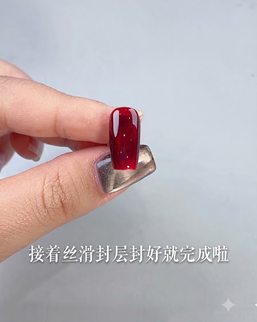 Una singola unghia rifinita con smalto gel rosso scuro lucido tenuta da un dito contro uno sfondo chiaro.