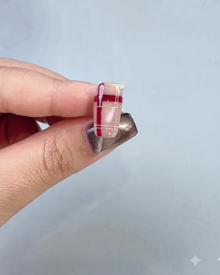 Primo piano di ununghia completata con un motivo a reticolo di cristallo rosso e design scozzese.