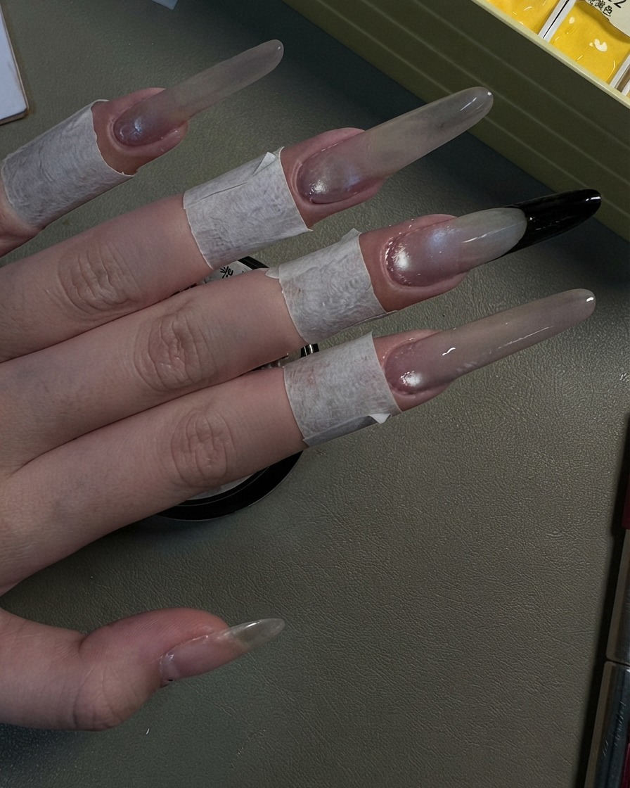 Una mano che mostra quattro unghie stiletto lunghe rifinite con un look cat-eye grigio perlato.