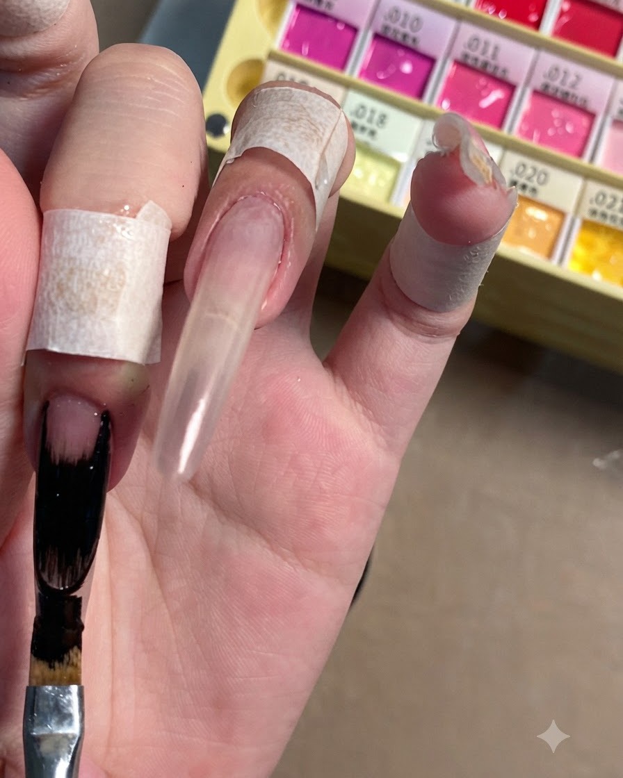 Un pennello piatto per nail art che applica gel nero coprente sulla punta allungata di ununghia stiletto trasparente.
