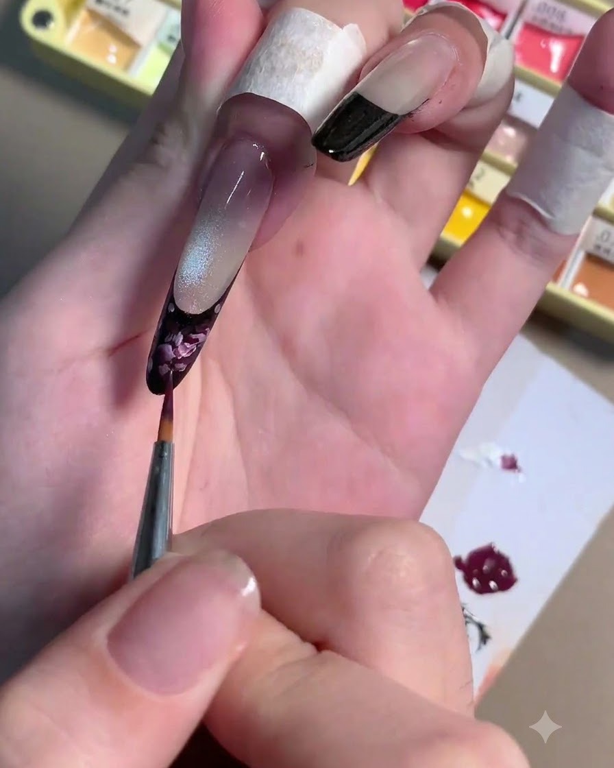 Un pennello liner sottile che applica tratti di gel rosa chiaro su una base di rosa prugna scuro su ununghia.