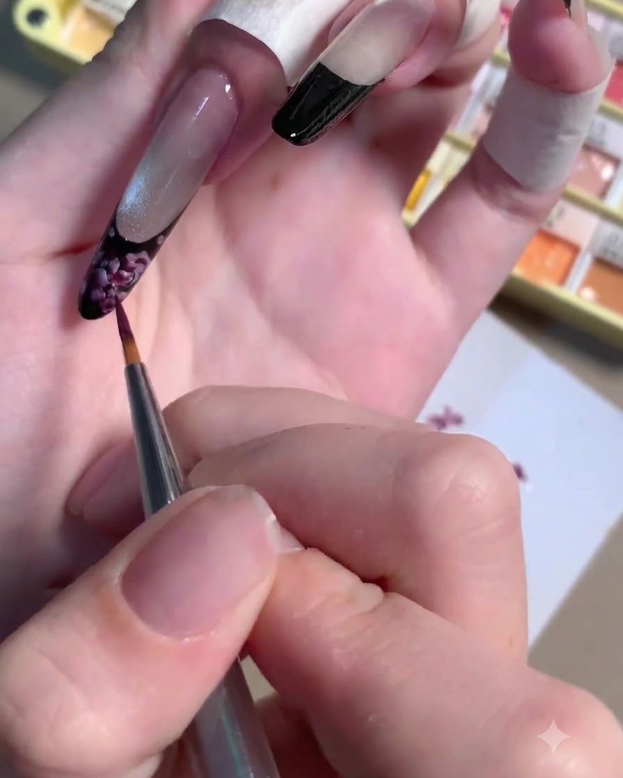 Un pennello liner sottile che applica un piccolo punto di gel prugna scuro al centro di una rosa dipinta.