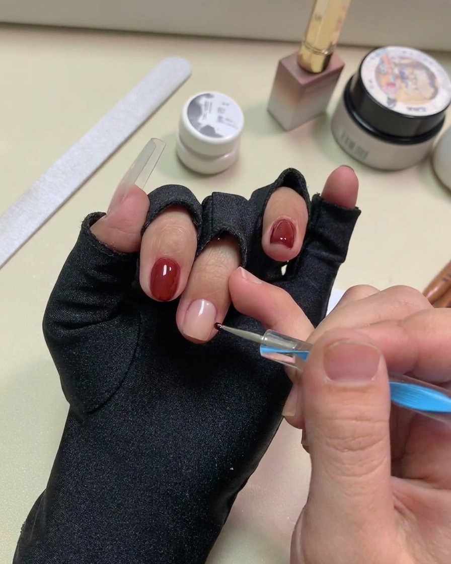 Undotting pen che posiziona piccoli puntini in gel nero sulla superficie dellunghia nude.