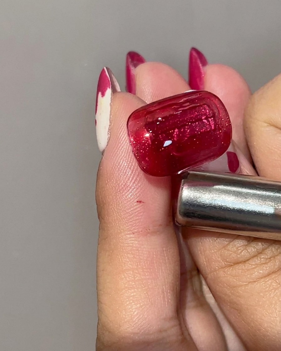 Primo piano di ununghia polimerizzata con gel cat eye rosso, che mostra un colore di base cremisi profondo con una striscia di luce magnetica concentrata.