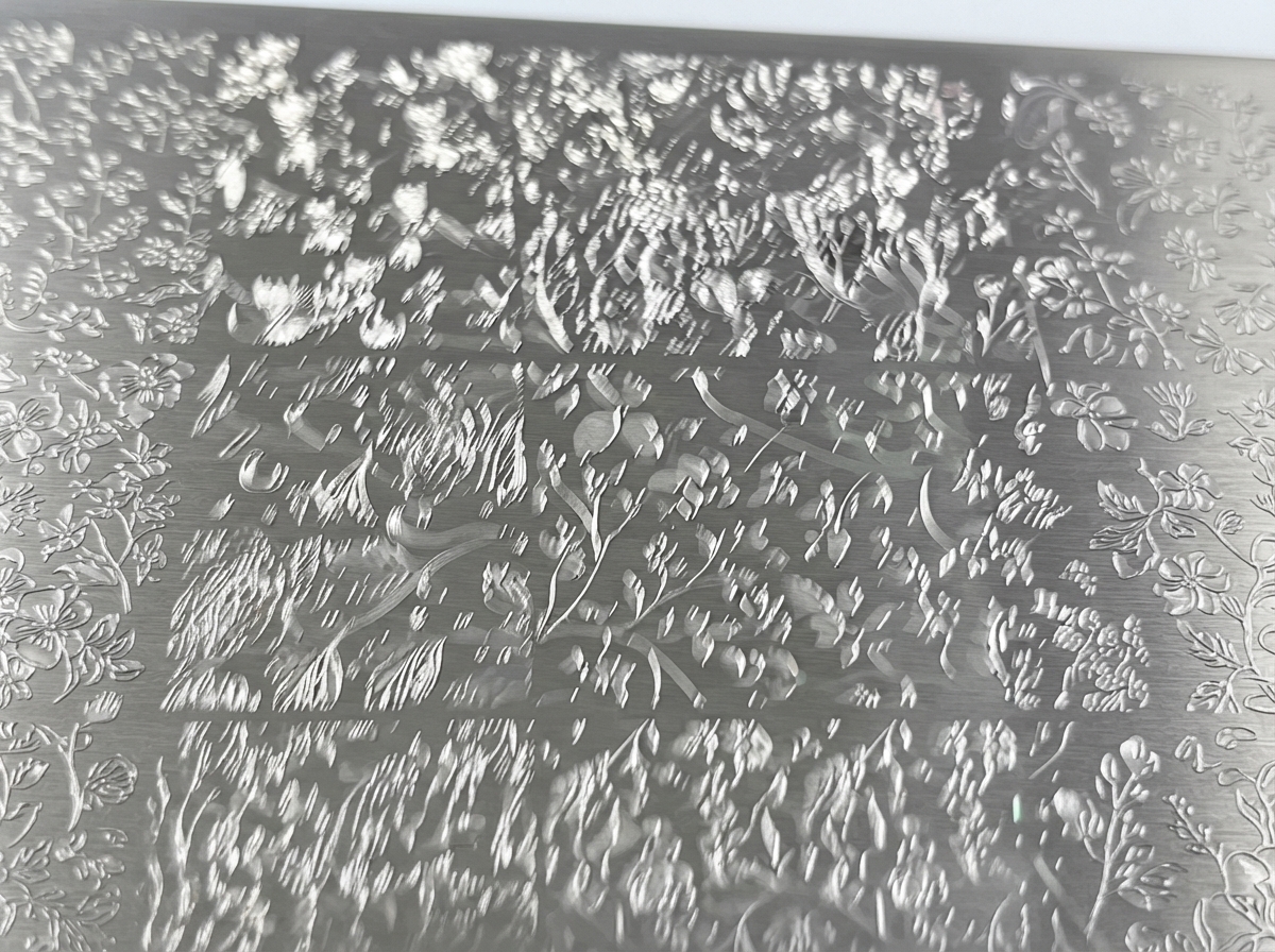 Primo piano di una piastra metallica per stamping incisa con dettagliati disegni floreali.