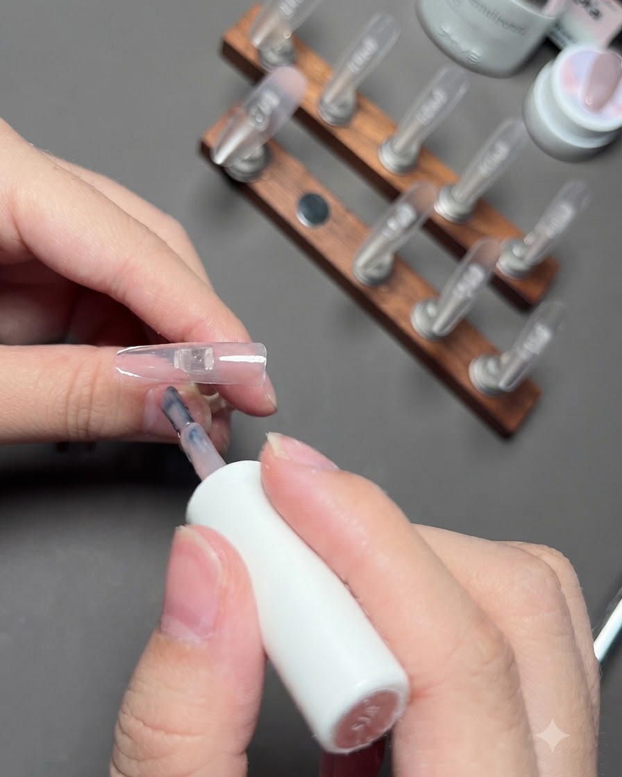 Un pennello che applica il gel color nude sullunghia dellanulare.