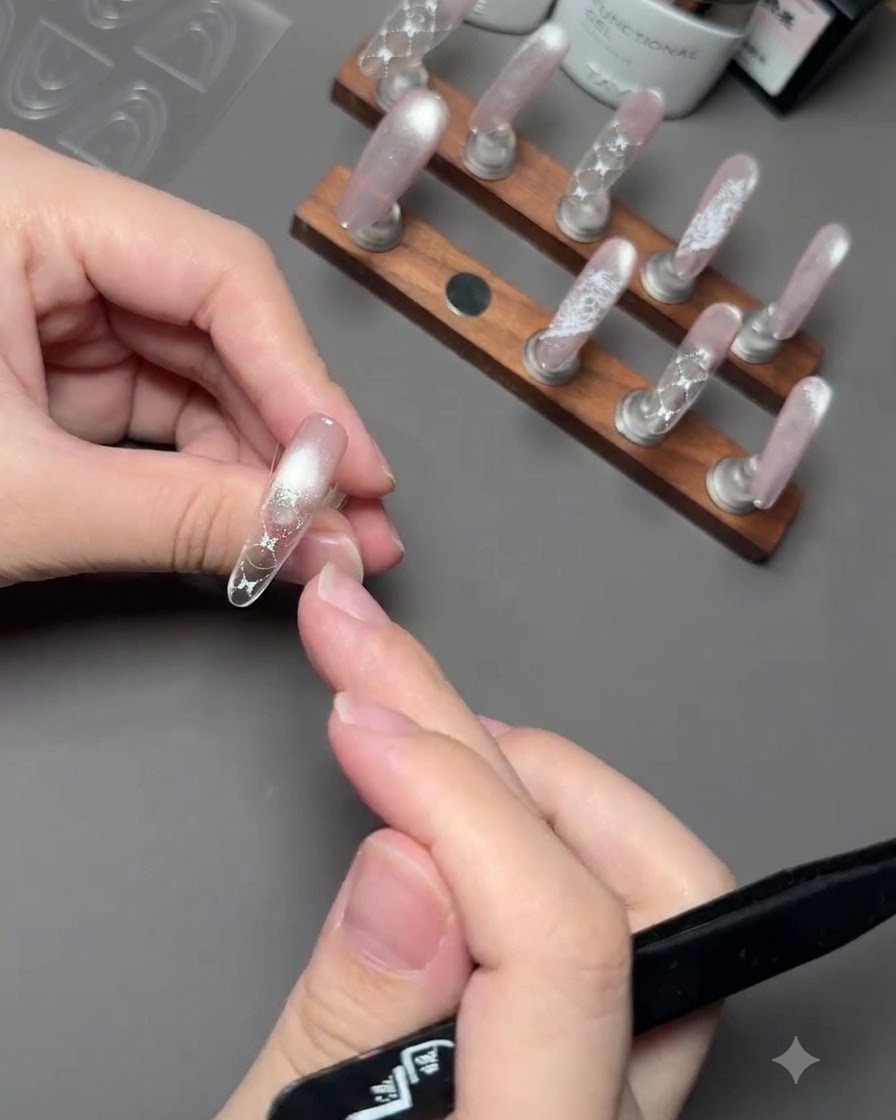 Una mano che tiene un pennello per applicare il gel semipermanente rosa sulla punta di ununghia sopra un adesivo guida.