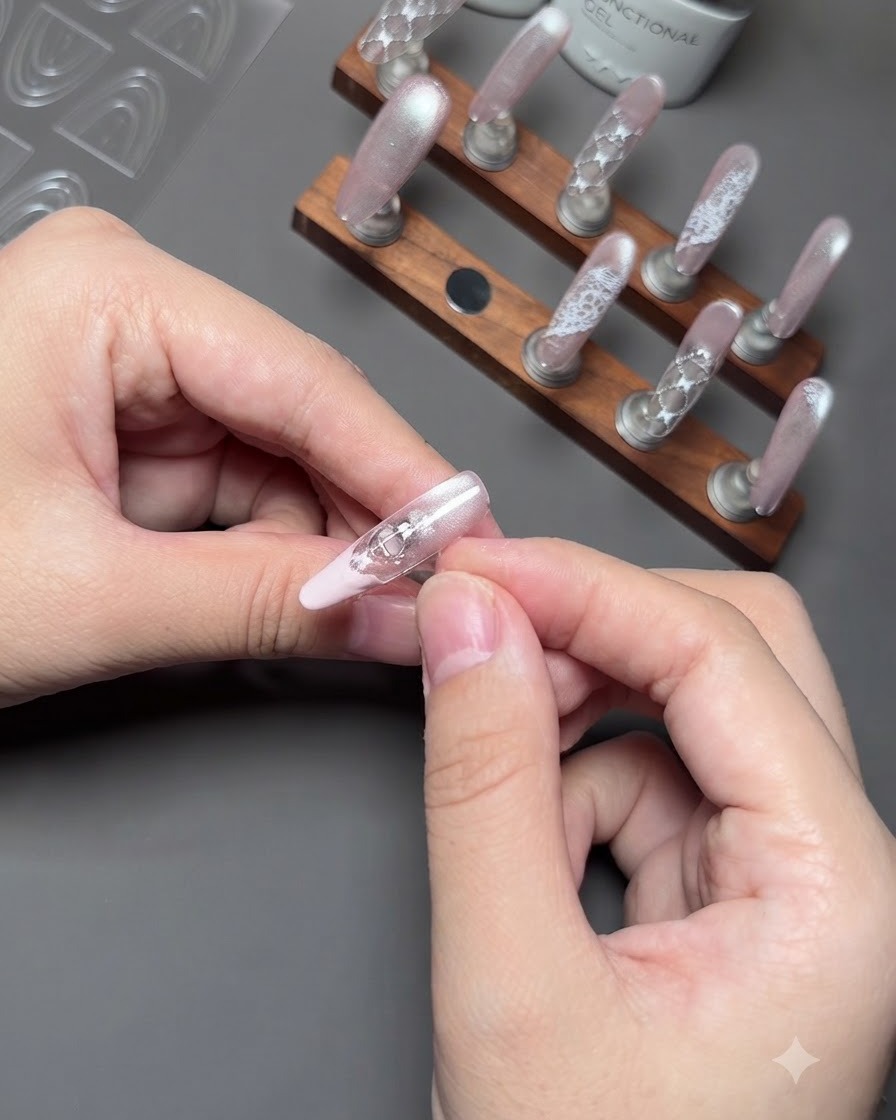 Un primo piano di dita che rimuovono delicatamente un adesivo guida da ununghia per esporre una pulita french tip rosa.