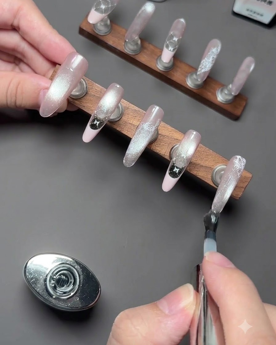 Un paio di pinzette di precisione che raccolgono un piccolo charm 3D a forma di gattino bianco.