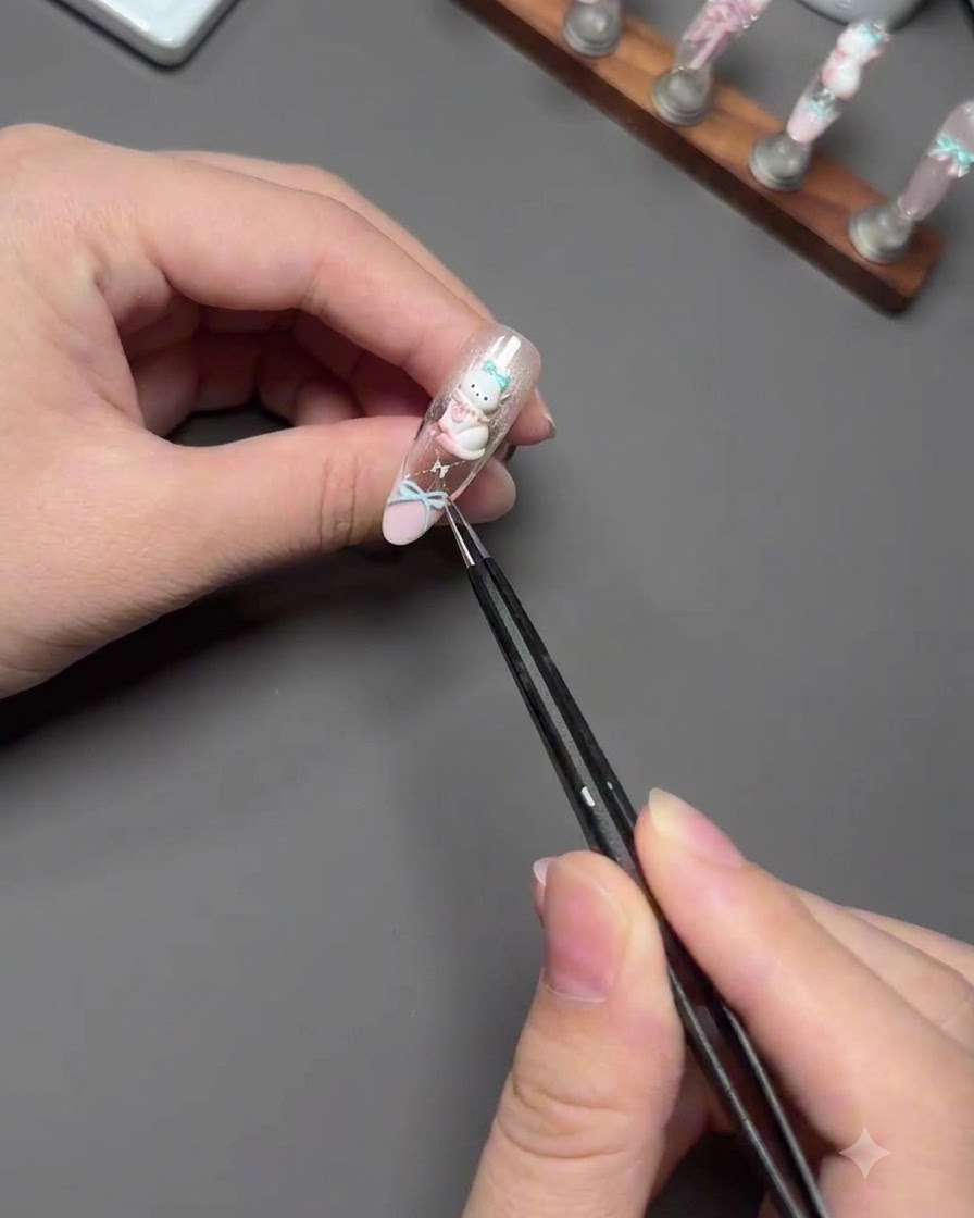 Pinzette che posizionano con cura un charm 3D a forma di gatto su ununghia decorata.