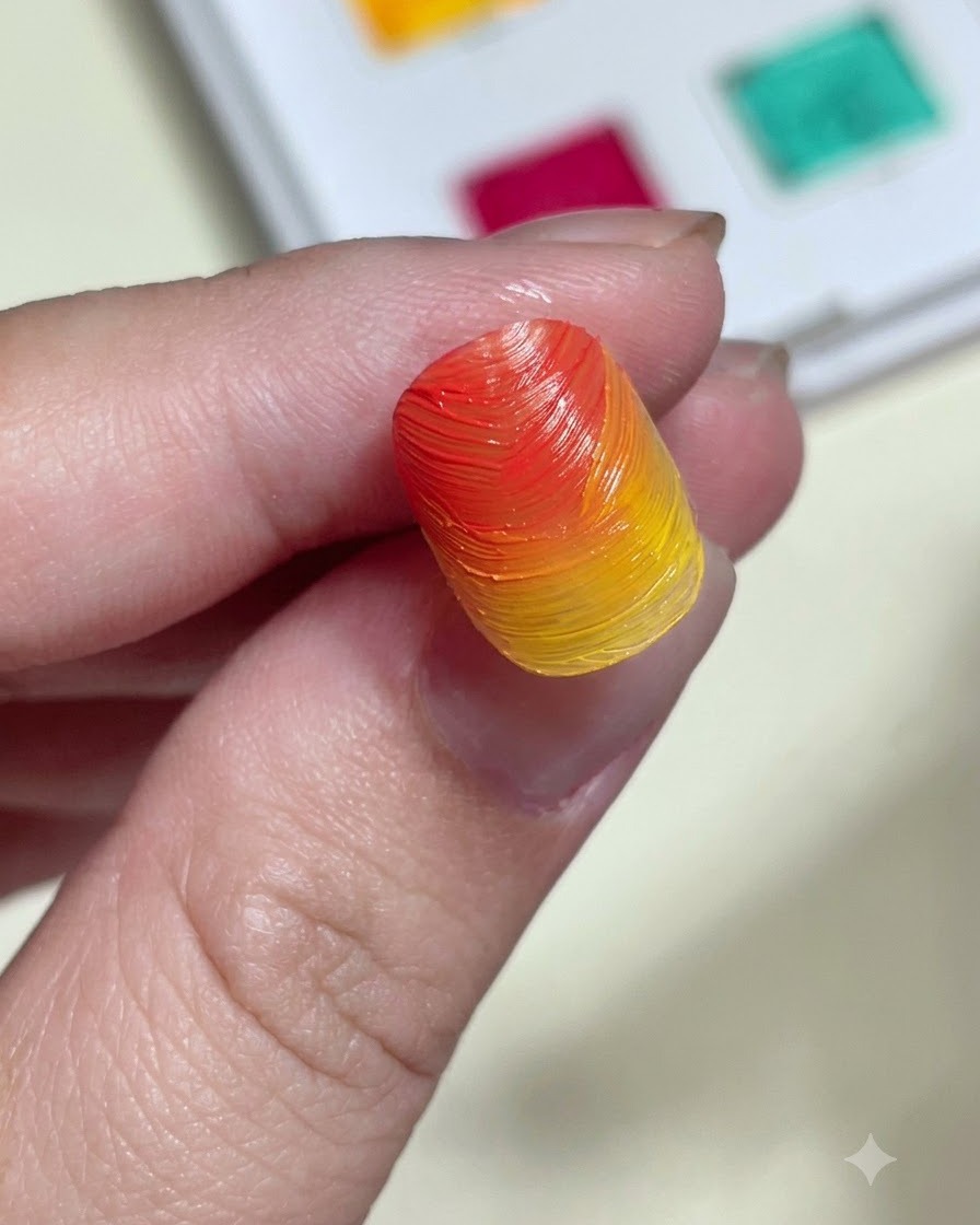 Un applicatore a spugnetta che strofina polvere aurora scintillante su una tip con gradiente arancione e giallo materico.