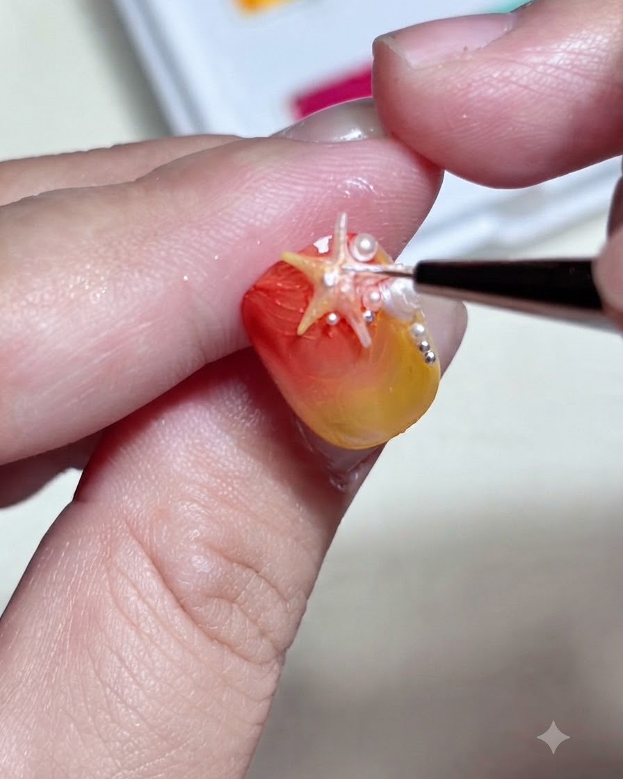 Un pennello fine che aggiunge puntini bianchi dettagliati e riflessi su un charm a forma di stella marina 3D montato su ununghia sfumata.