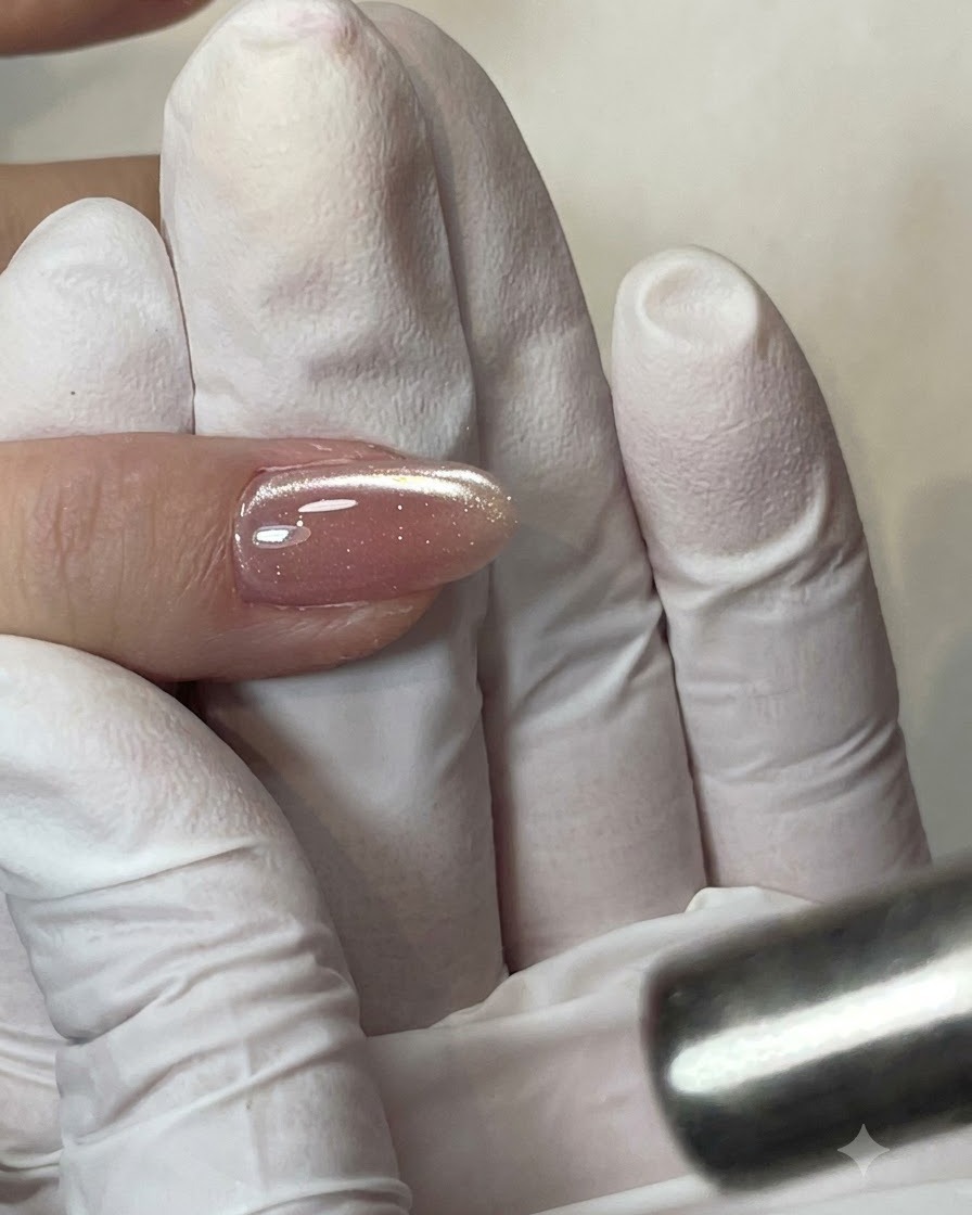 Un pennello per gel piatto che applica uno strato trasparente di base coat sulla lamina ungueale.