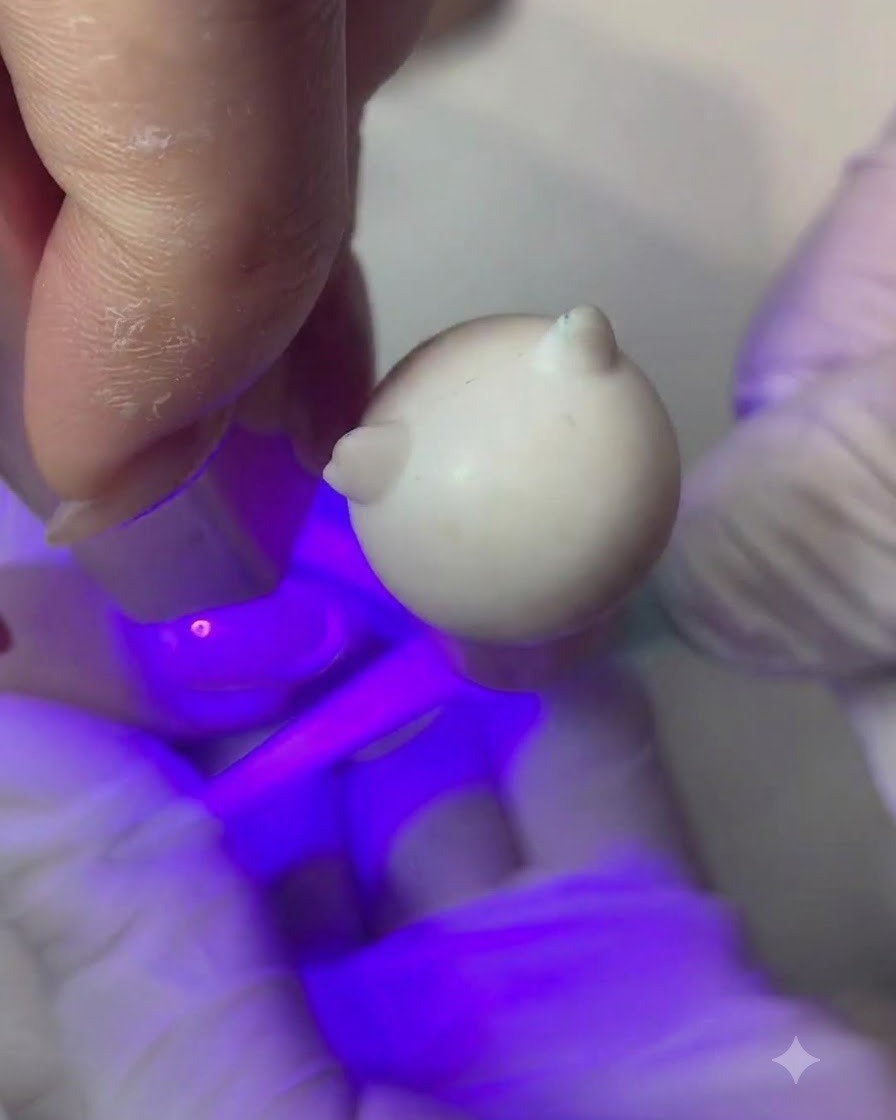 Un pennello sottile che applica un sottile strato di gel color pesca nude su ununghia.