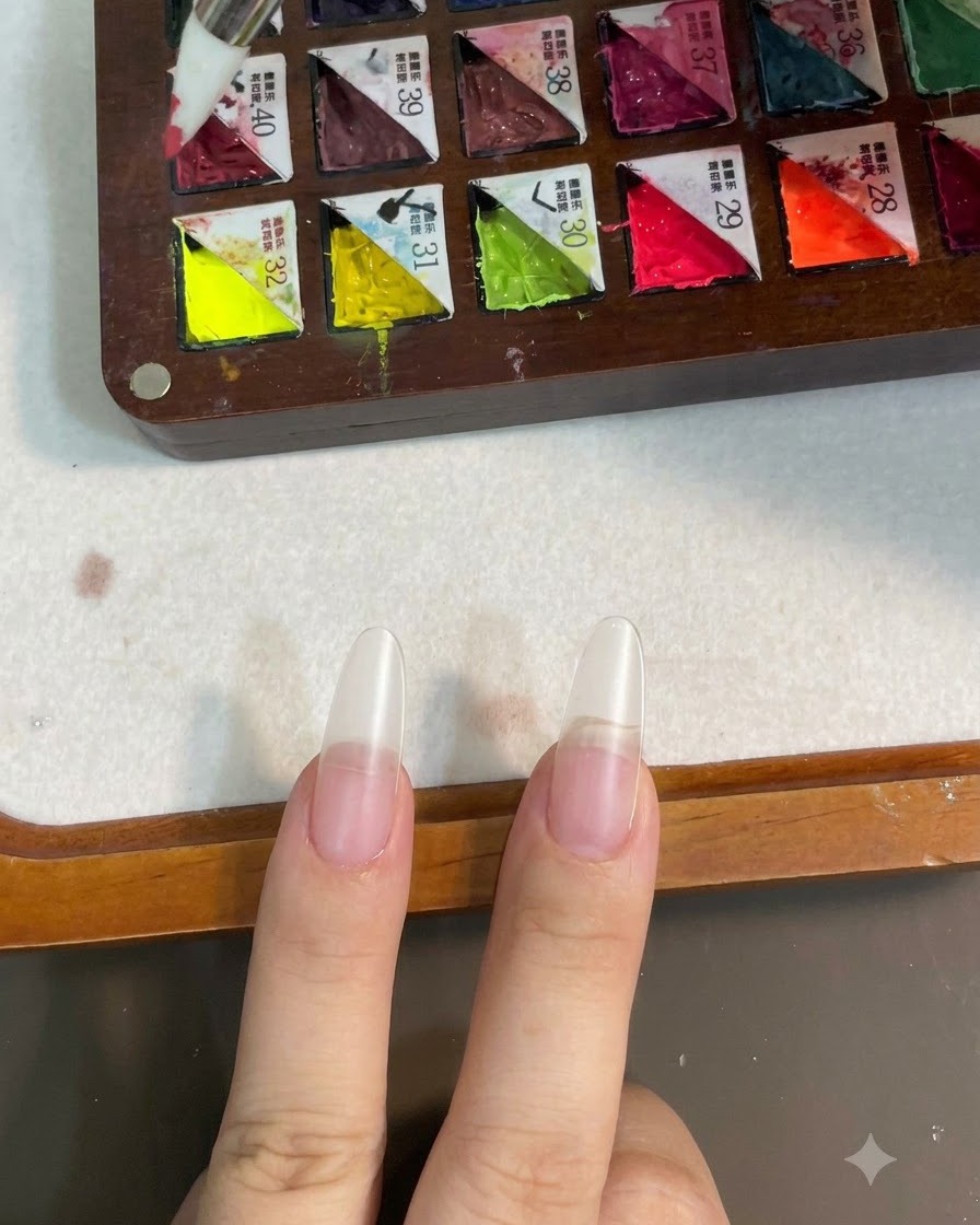Un pennello in silicone che preleva il gel colorato rosa da una tavolozza a scomparti.