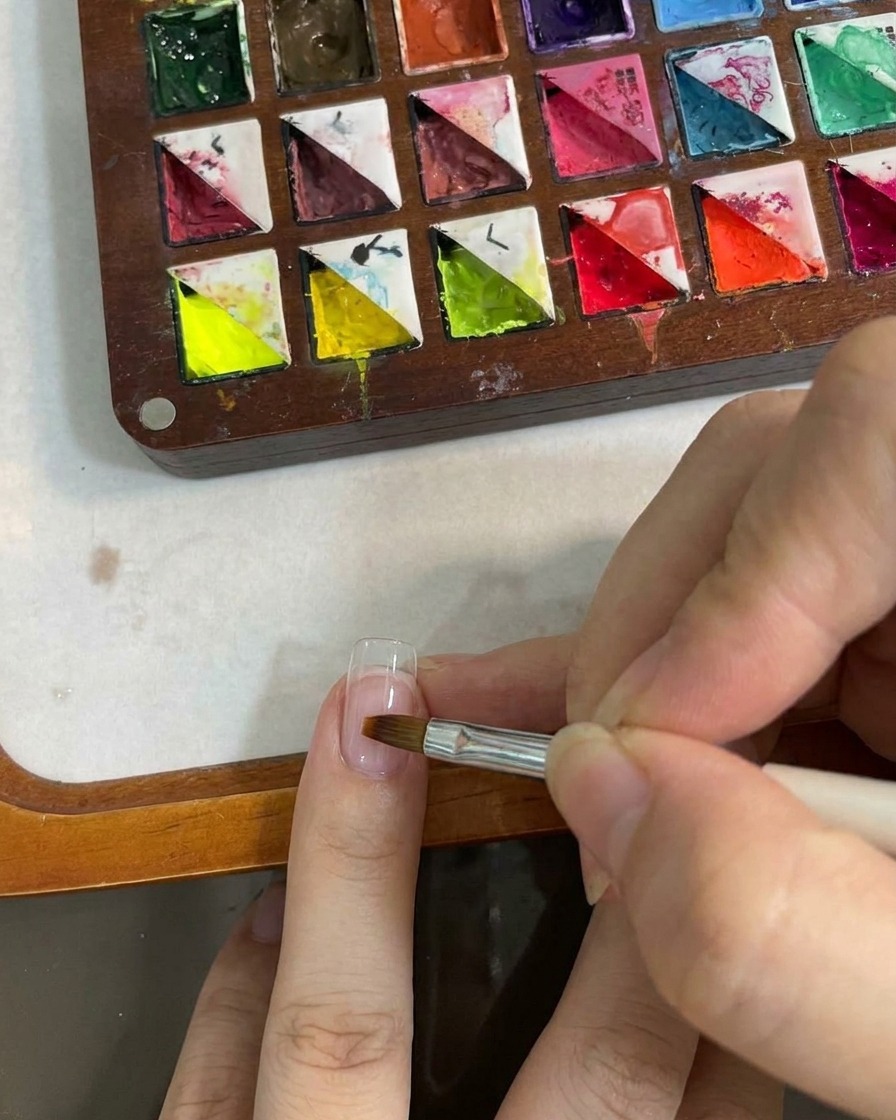 Un pennello piatto che sfuma il colore sullunghia.