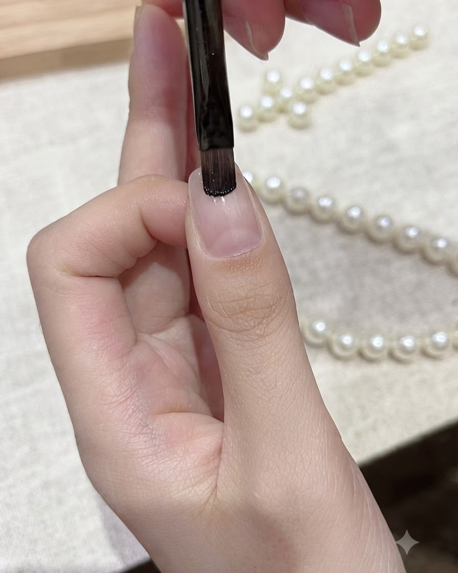 Un pennello piatto per gel applica lo smalto gel nero direttamente sul margine libero di ununghia naturale.