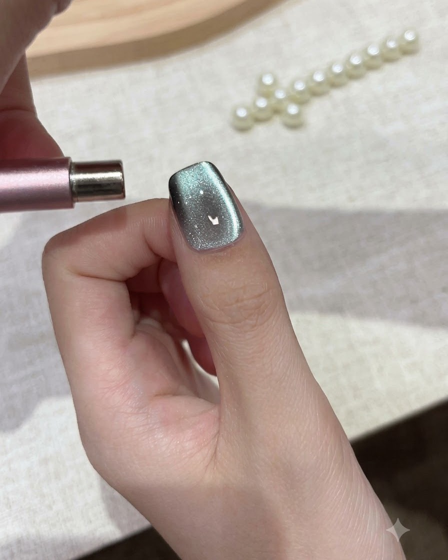Un magnete cilindrico tenuto parallelamente alla punta dellunghia per modellare le particelle di gel cat eye.