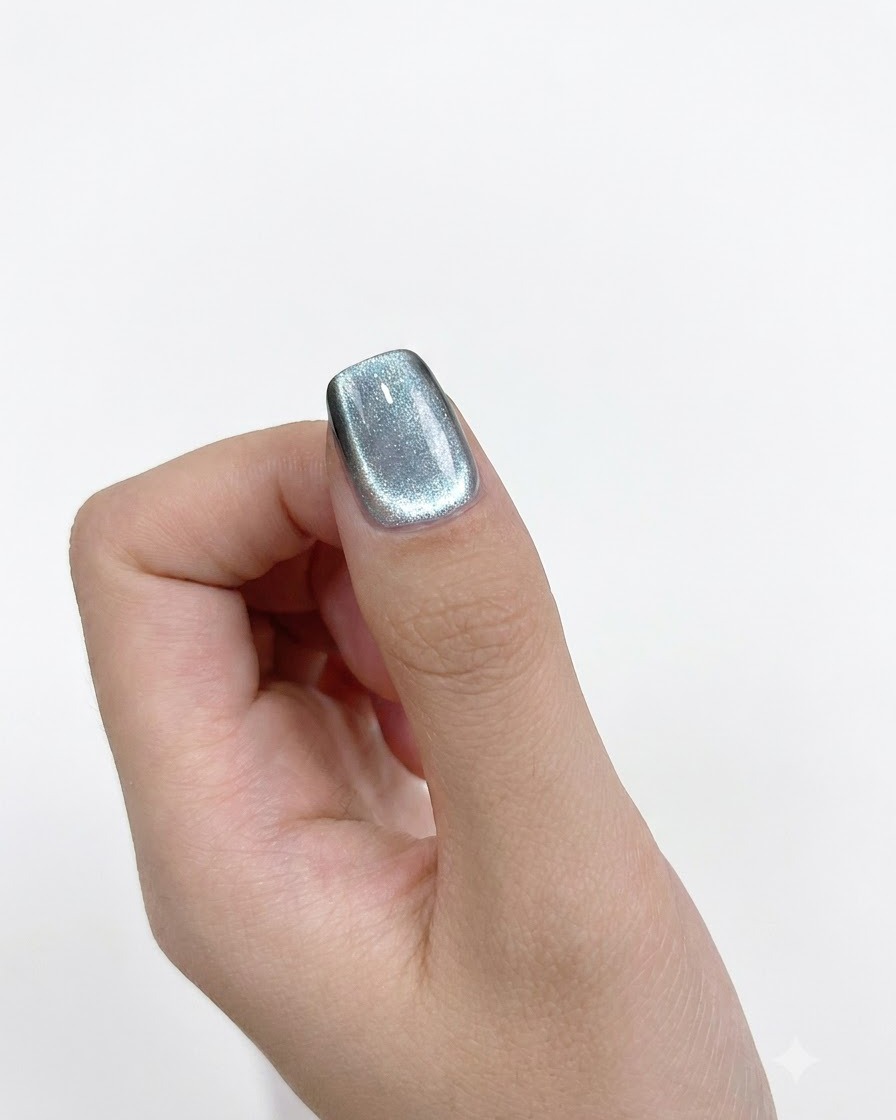 Una vista ravvicinata di un magnete cilindrico tenuto precisamente contro il lato sinistro di ununghia dipinta.