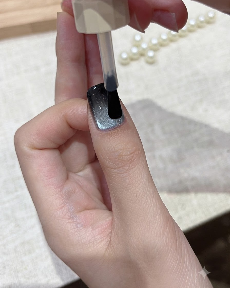 Un pennello che fa scivolare uno strato di top coat lucido trasparente sopra il design finito delle unghie cat-eye.