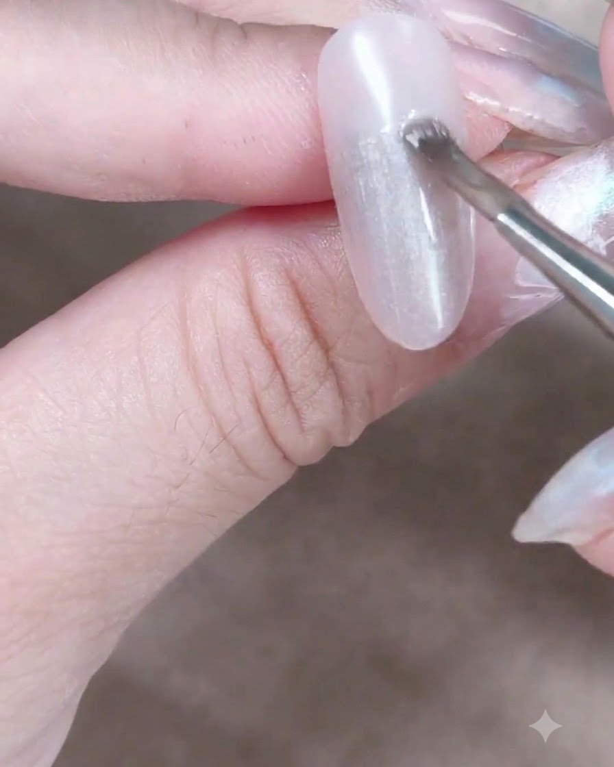 Un magnete cilindrico tenuto vicino a ununghia con gel cat-eye fresco per spostare e orientare le particelle di riflesso magnetico.