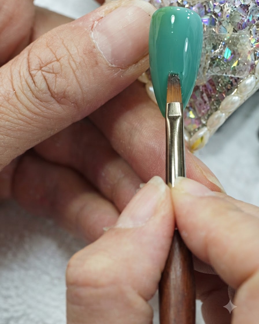Un pennello piatto per nail art che esegue delicati tratti verticali attraverso il centro di ununghia con sfumatura verde e teal.