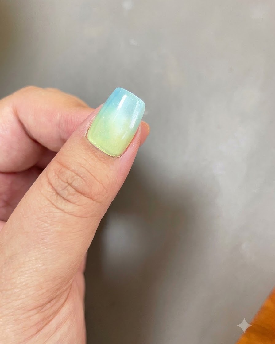 Ununghia con una base sfumata da blu a giallo e un effetto di luce magnetica cat eye circolare posizionata sotto una lampada di polimerizzazione viola UV/LED.