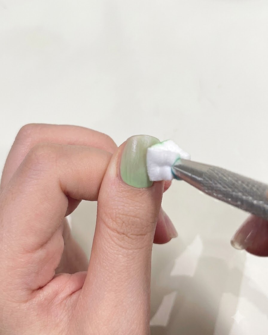 Un pollice posizionato sotto una mini torcia UV/LED compatta per polimerizzare lo smalto gel.